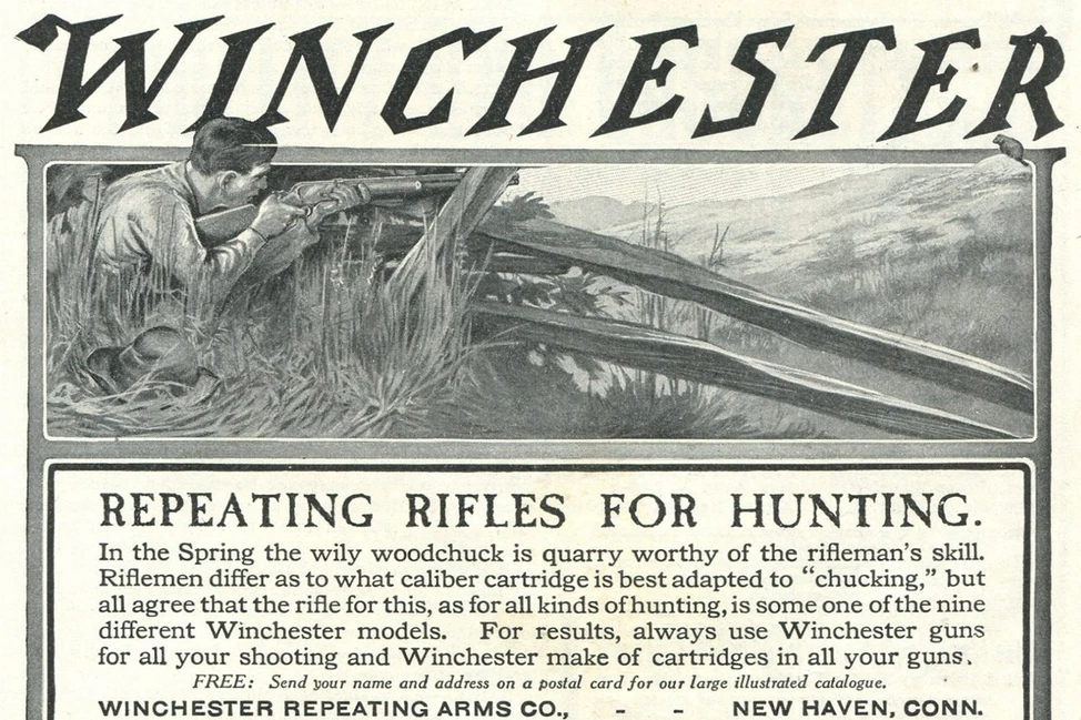 Реклама начала XX века компании Winchester: охотник с винтовкой лежит в траве, текст продвигает многозарядные ружья для охоты