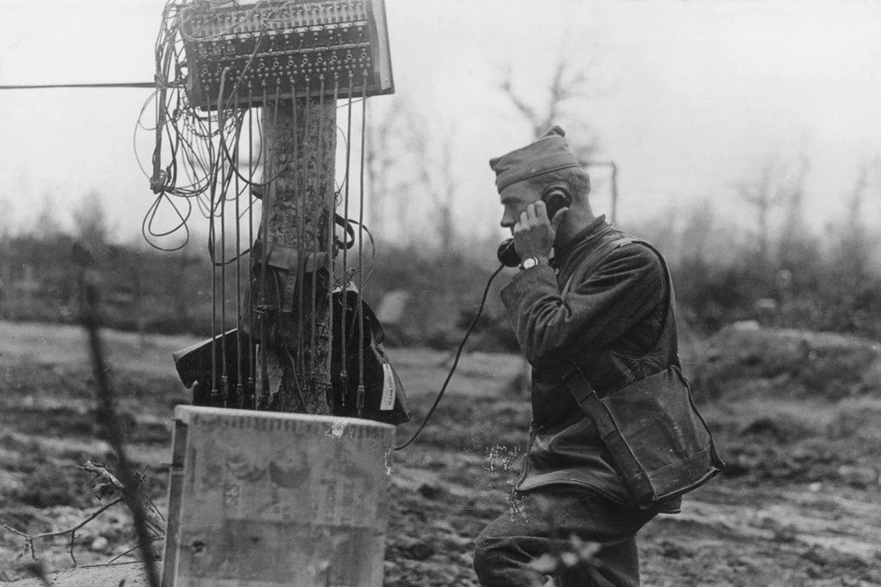 Солдат с телефонной трубкой у полевого коммутатора с множеством проводов