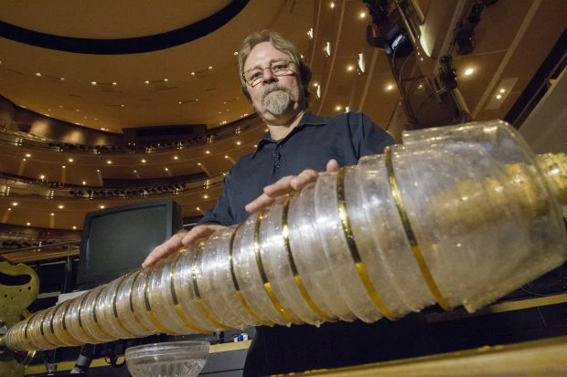 Мужчина играет на стеклянной гармонике с вращающимися стеклянными чашами на сцене концертного зала