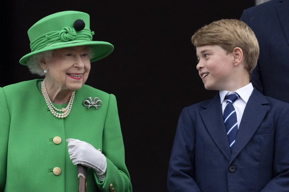 Елизавета II в ярко-зелёном костюме и шляпе улыбается принцу Джорджу в тёмно-синем костюме