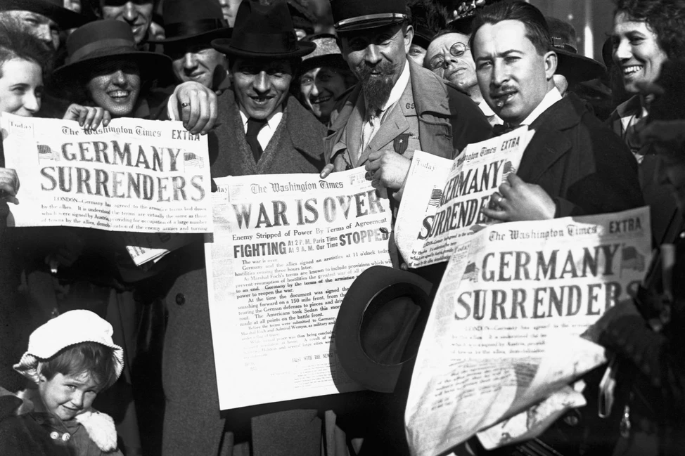 Толпа американцев с газетами The Washington Times с заголовками Germany Surrenders и War Is Over, 1918 год