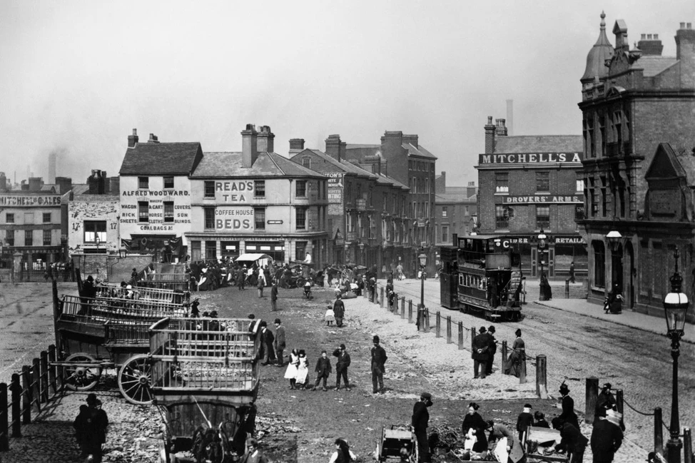 Улица Бирмингема 1890-х с паровым трамваем, двухэтажными зданиями с вывесками, повозками и людьми в викторианской одежде