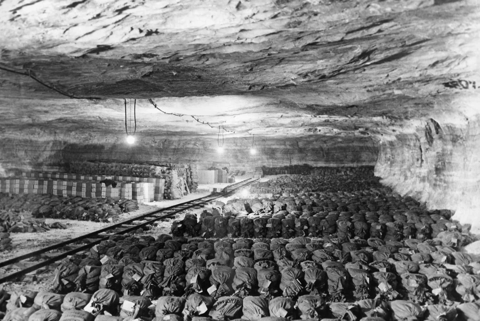 Мешки со слитками на полу шахты Меркерс под сводами с рельсами и лампами