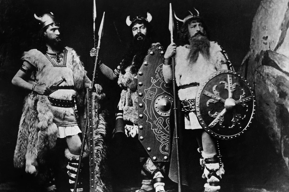Три актёра в рогатых шлемах и меховых одеждах викингов со щитами и копьями, чёрно-белая театральная постановка