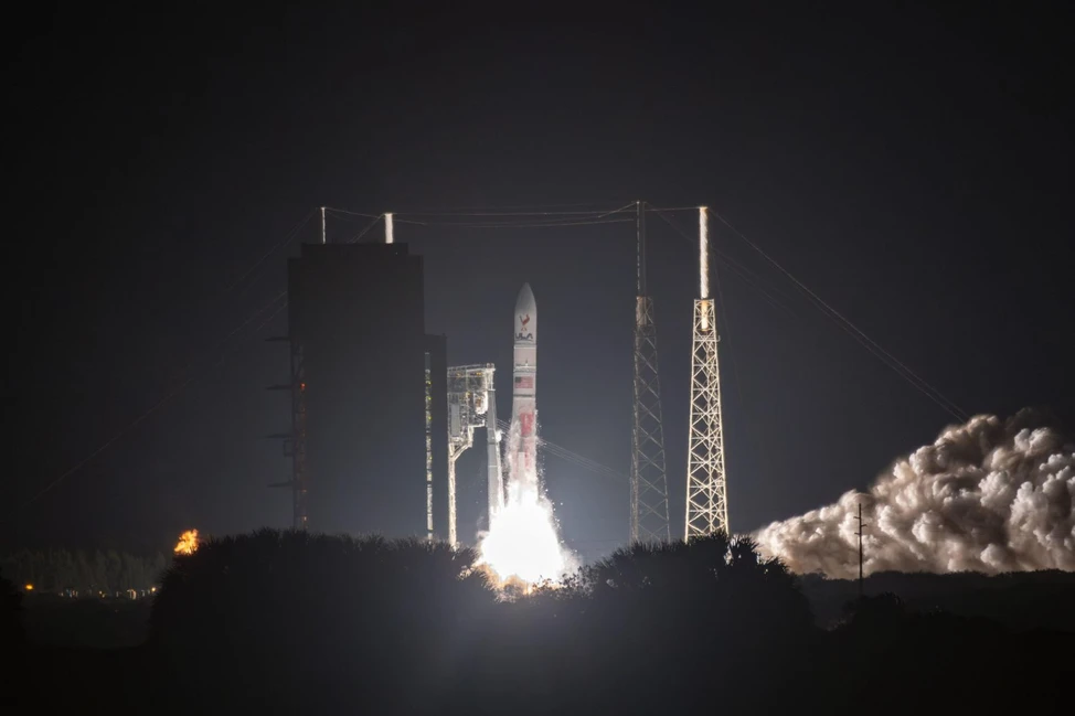 Ночной запуск ракеты: яркое пламя двигателей, клубы дыма, силуэты стартовых башен на тёмном небе