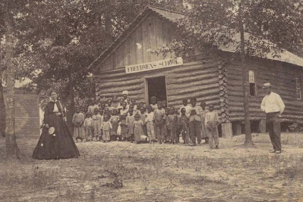Группа детей и взрослых у деревянной школы Freedmen’s School в США, около 1868 года