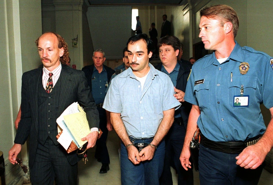 Томаса Грассо в наручниках сопровождают полицейские и адвокат в коридоре суда